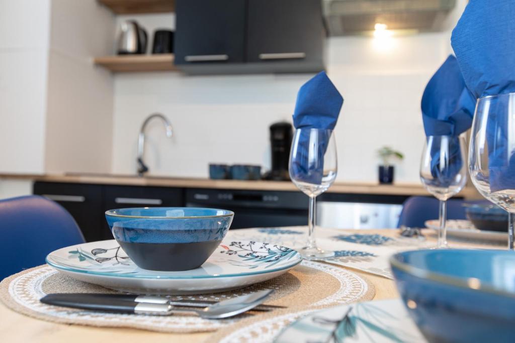 a table with blue dishes and wine glasses on it at Le Sans Souci @Chique@Moderne@Proche du centre-ville 3pieces 2 Chambres in Colmar