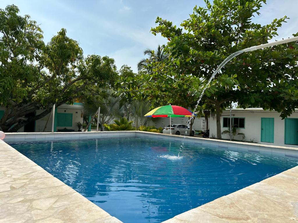 uma piscina com um guarda-sol verde e vermelho em Costa de Vikingos em Tolú