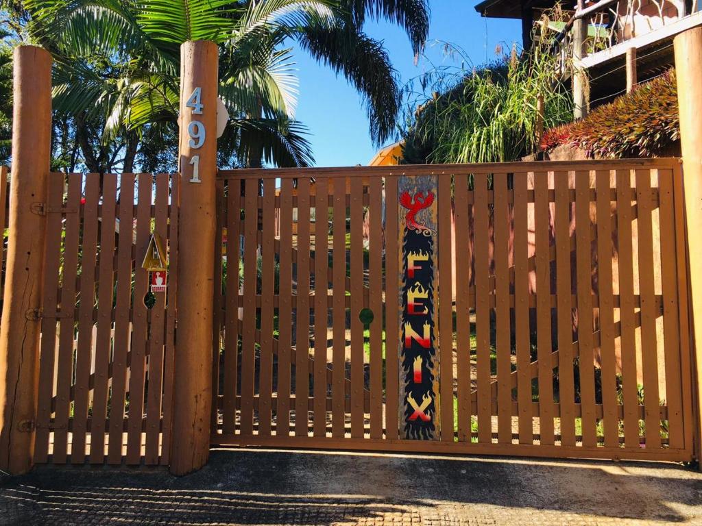 a wooden fence with a gate with a colorfulfullypainted gate sidxhaarhaarhaar at Chalés Fenix in Santo Antônio do Pinhal