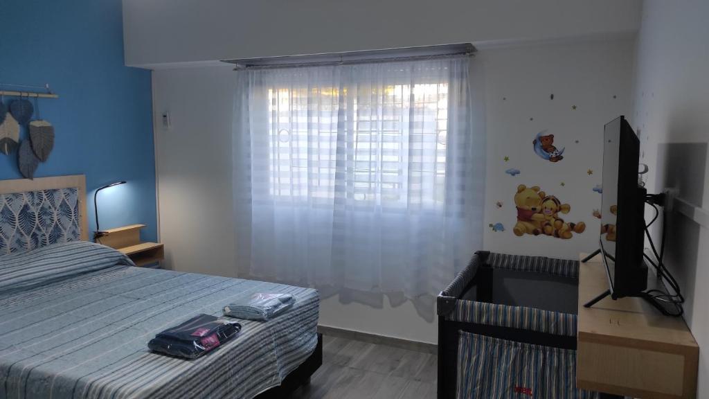 1 dormitorio con 1 cama, TV y ventana en casa a 20 minutos del aeropuerto de Ezeiza sobre avenida opcional tranfer amplio parque para mascotas rejas y cámaras de seguridad en Monte Grande