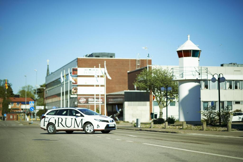 a white car parked on the street next to a lighthouse at STF Hotell Rum Oscar in Oskarshamn