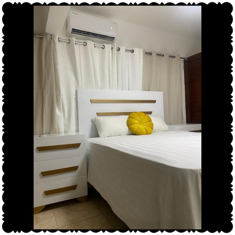 a bedroom with a white bed with a yellow pillow at Apartment in the best of puerto Plata in San Felipe de Puerto Plata