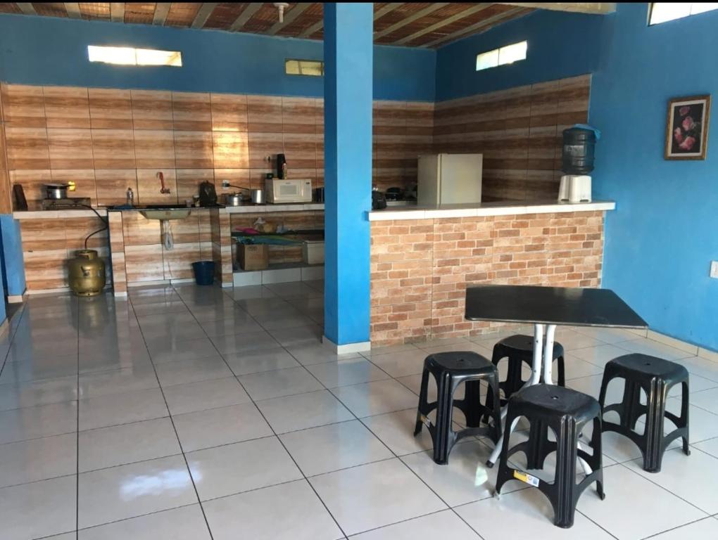 a kitchen with a table and some black stools at Quarto com ar condicionado, WiFi in Tareco