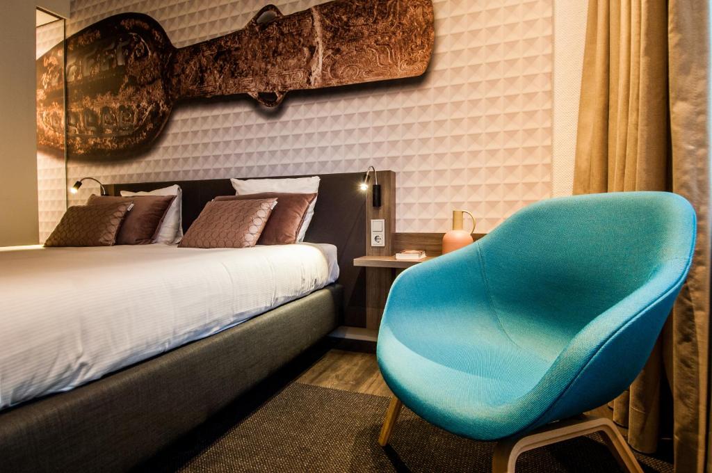 a bedroom with a blue chair next to a bed at Golden Tulip Leiden Centre in Leiden