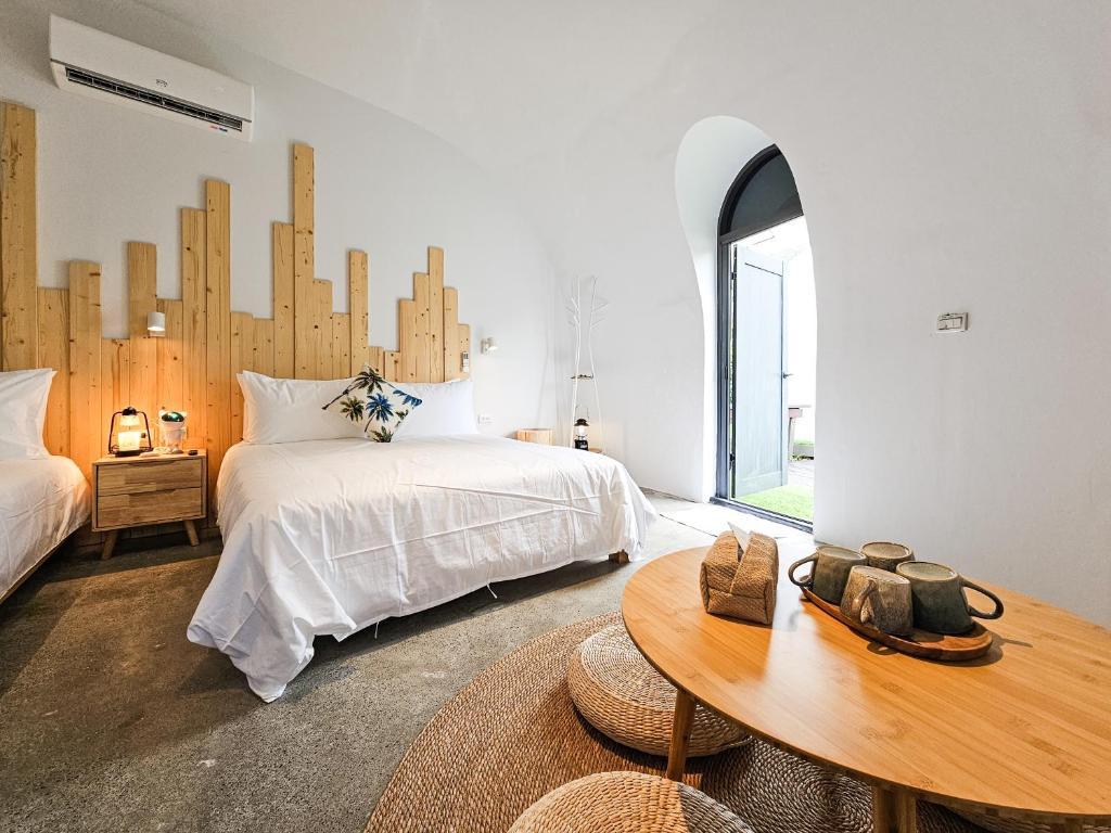Dormitorio blanco con cama y cabecero de madera en 墾丁圓石灘 Kenting Pebble Beach, en Shizi