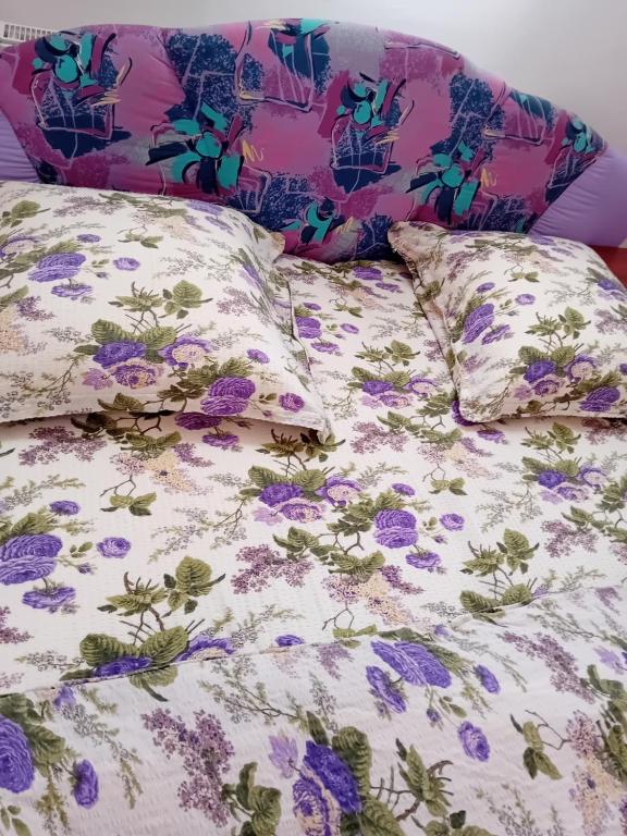 Bett mit lila Blumen und Kissen in der Unterkunft Casa Dănuț in Reşiţa