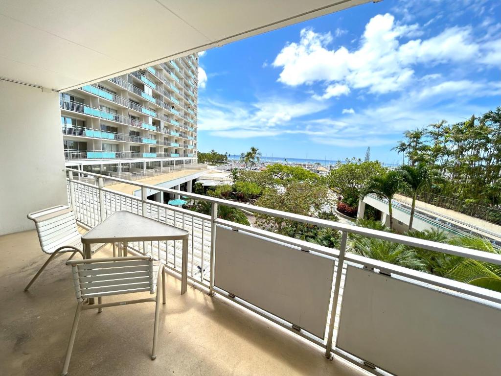 balcón con mesa, sillas y vistas al océano en Ilikai Apt 308 - Spacious Studio with Stunning Ocean & Harbor Views en Honolulu