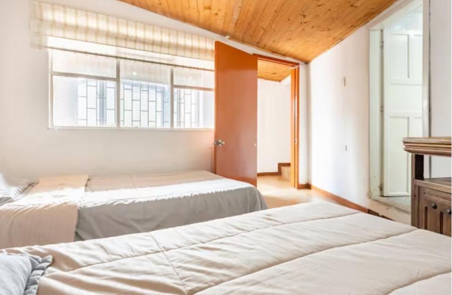 two beds in a room with a window at CASA FLORES in Bogotá