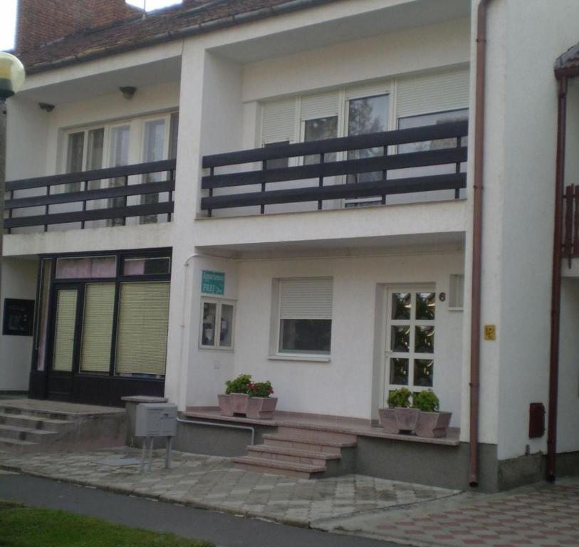 a white house with potted plants in front of it at Jartó Apartman in Harkány