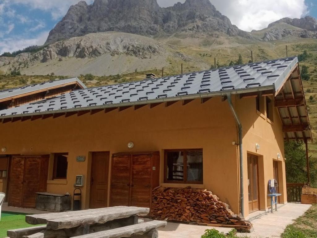 une maison avec un tas de bois de chauffage et une montagne dans l'établissement Grand Chalet 5 pièces, 15 pers., cheminée, parking privé - Le Monêtier-les-Bains - FR-1-762-42, au Monêtier-les-Bains