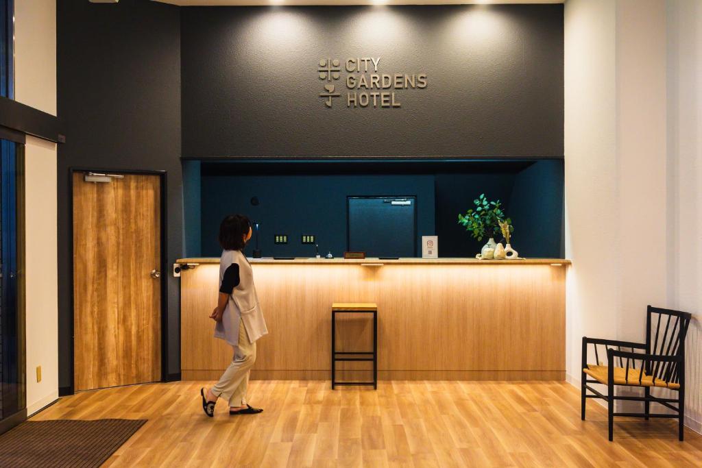 a woman walking past the lobby of a hotel at 米子シティガーデンズホテル Yonago Citygardens Hotel in Yonago