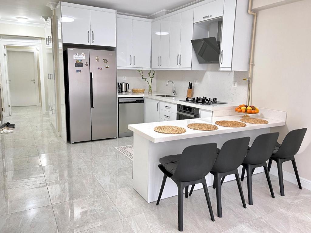 una cocina con armarios blancos y una barra con sillas en NEW Citrus Garden Home Duplex, en Mudanya