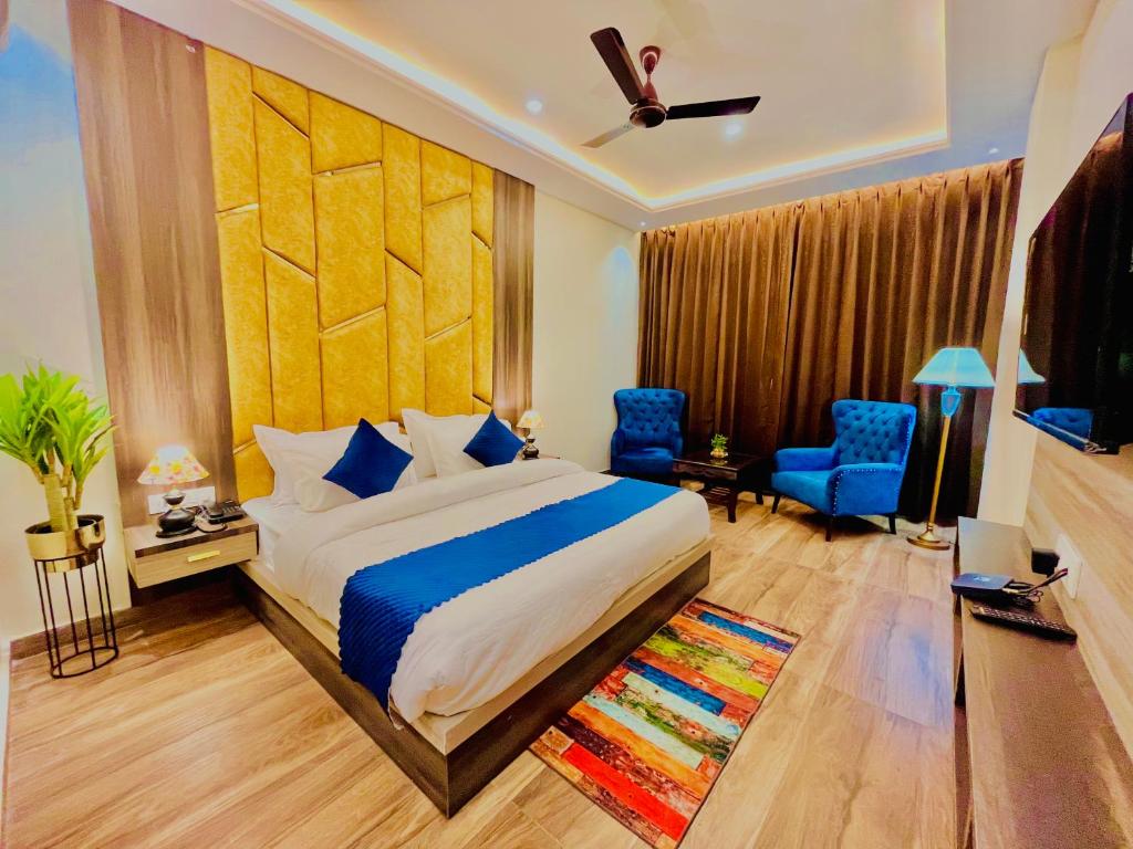 Schlafzimmer mit einem Kingsize-Bett und blauen Stühlen in der Unterkunft Ganges Blossam, Haridwar-Rishikesh Road - A Four Star Luxury Hotel in Rishikesh