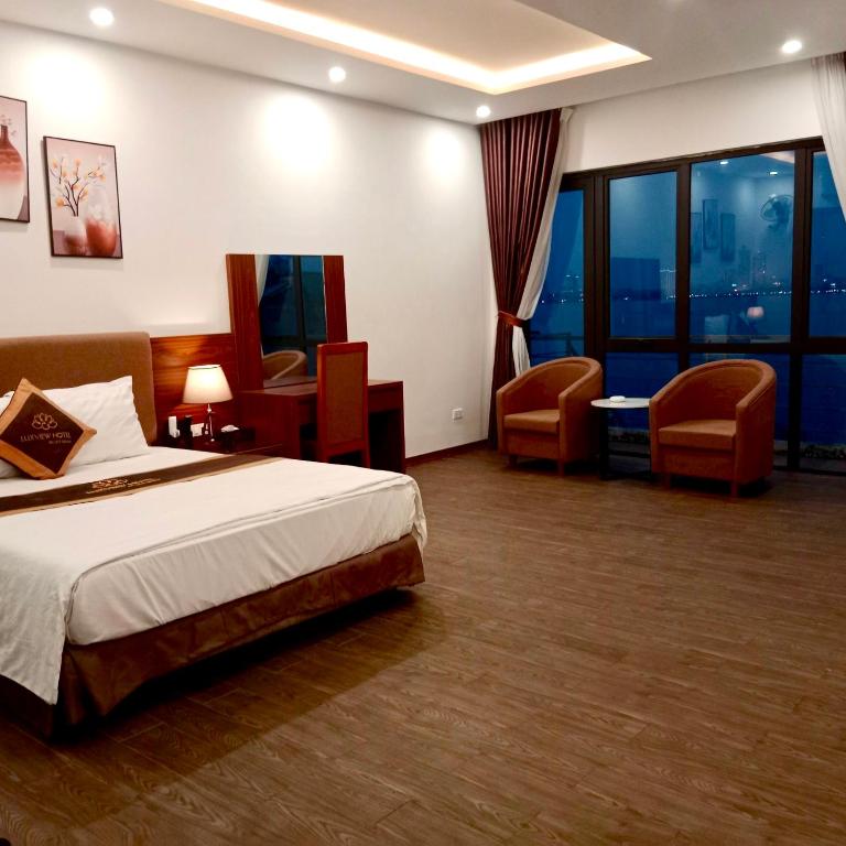 a hotel room with a bed and two chairs at LuxTel Hotel Tây Hồ in Hanoi