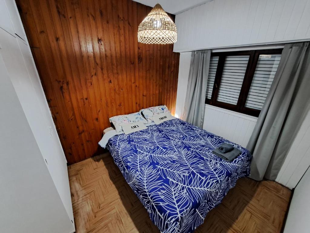 a small bedroom with a bed with a blue comforter at Hostel Belgrano Home in Monte Grande