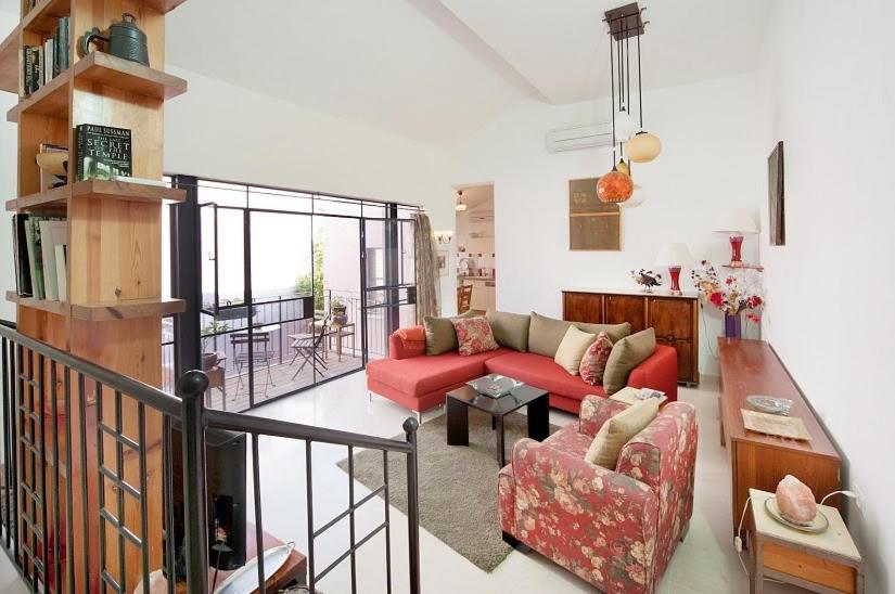 ein Wohnzimmer mit einem roten Sofa und einem Tisch in der Unterkunft Lovely 2BR Apt w Balcony in Neve Tzedek Area Sea N' Rent in Tel Aviv