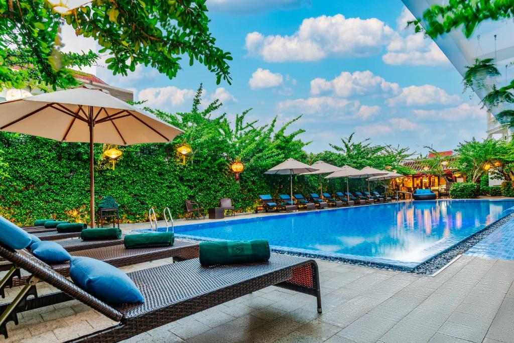 a pool at a resort with chairs and umbrellas at Wyndham Garden Hoi An Cua Dai Beach in Hoi An