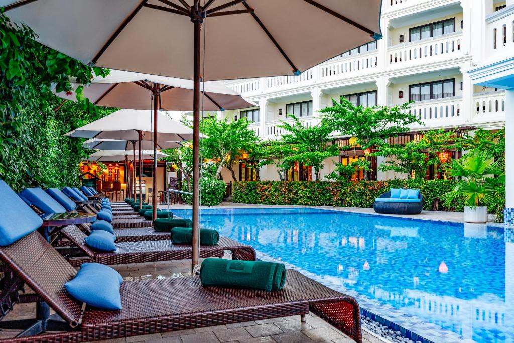 a pool at a hotel with chairs and umbrellas at Wyndham Garden Hoi An Cua Dai Beach in Hoi An