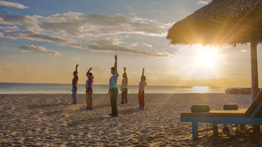 a group of people doing yoga on the beach at Wyndham Garden Hoi An Cua Dai Beach in Hoi An
