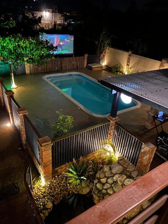 a swimming pool at night with a tv in the background at Pousada Morrison in Praia do Rosa