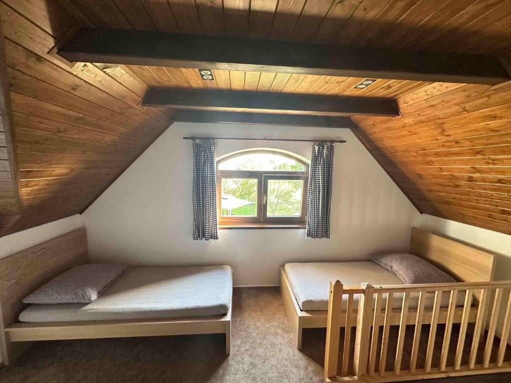 Cette chambre mansardée comprend 2 lits et une fenêtre. dans l'établissement Penzion - Apartman Přestavlky, à Tršice