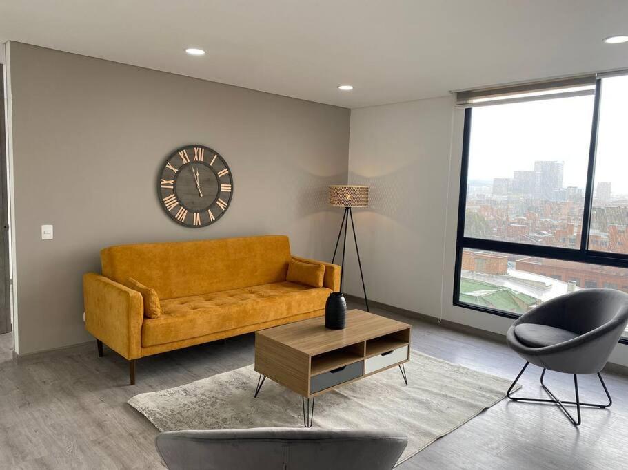 a living room with a couch and a clock on the wall at Amplio apartamento con excelente vista in Bogotá