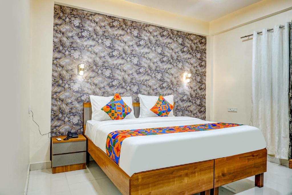 Un dormitorio con una cama con una pared de acento floral en FabHotel ATS Inn, en Pune