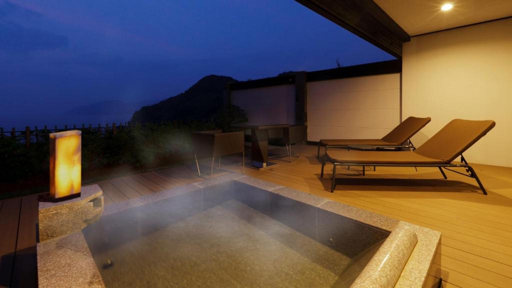 a patio with a pool and a table and a television at Fugaku Gunjo in Izu