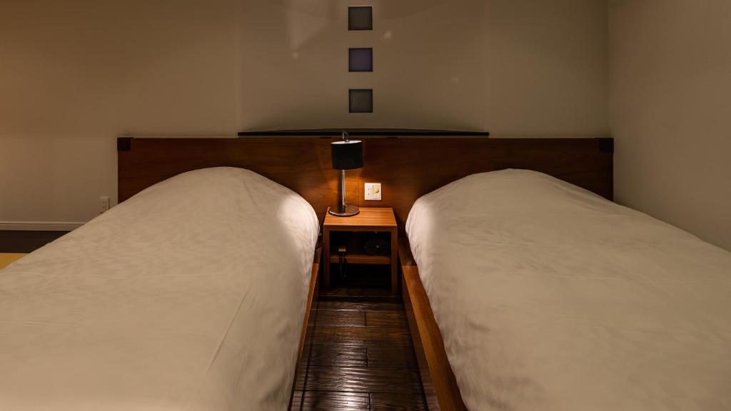 two twin beds in a room with a night stand at Fugaku Gunjo in Izu