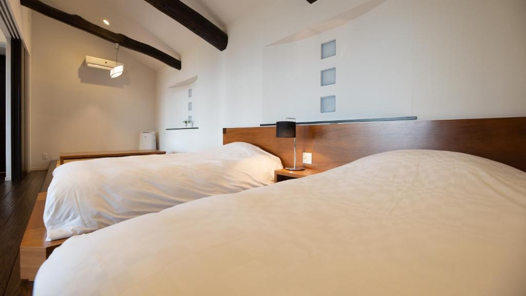 two beds in a bedroom with white sheets at Fugaku Gunjo in Izu