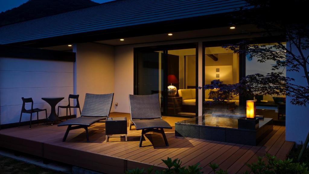 a deck with chairs and a table and a living room at Fugaku Gunjo in Izu