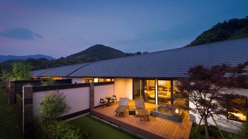 a house with a deck with chairs and a backyard at Fugaku Gunjo in Izu
