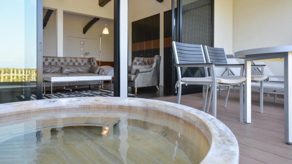 a hot tub in the middle of a room with chairs at Fugaku Gunjo in Izu