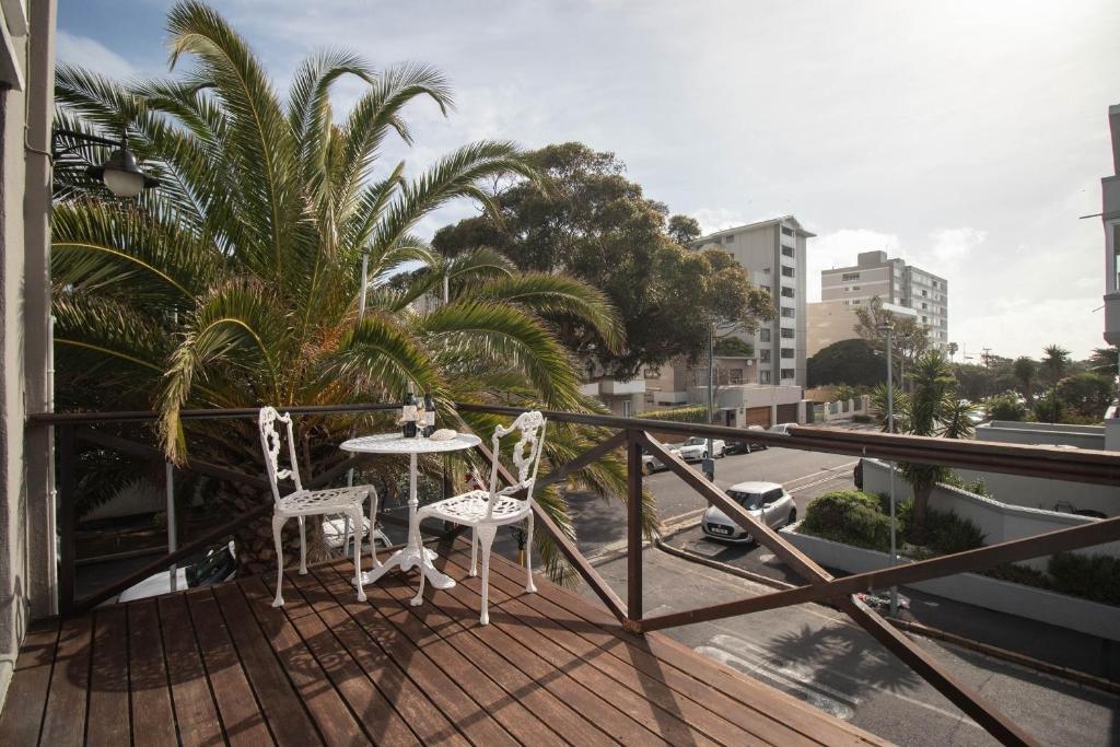 balcón con mesa, 2 sillas y una palmera en Spring Tide Inn by CTHA, en Ciudad del Cabo
