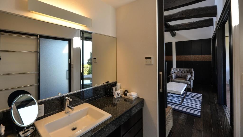 a bathroom with a sink and a mirror and a chair at Fugaku Gunjo in Izu