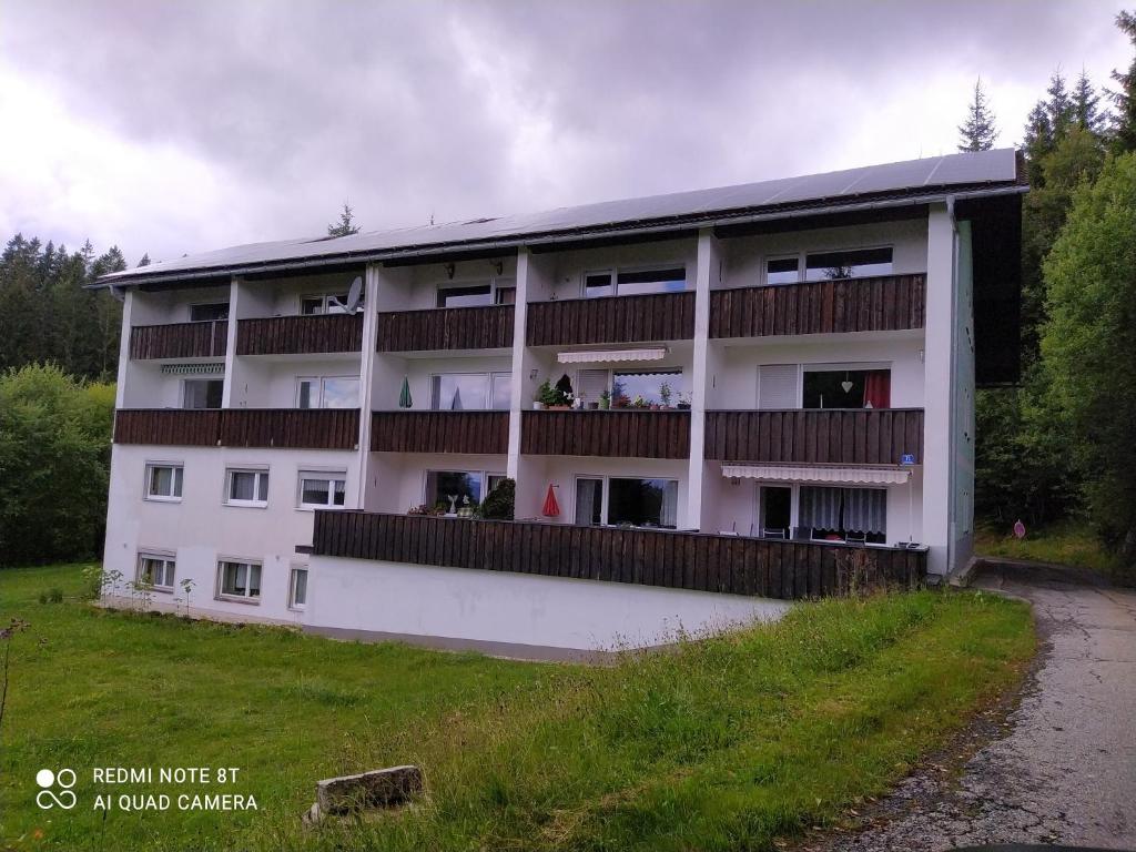 a white apartment building with balconies and a field at Appartementhaus Tannenhof - Wohnung 2 in Haidmühle