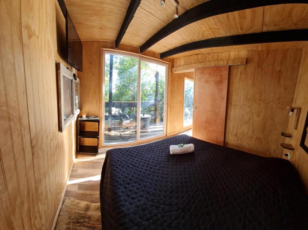 - une chambre avec un lit noir dans une pièce dotée d'une fenêtre dans l'établissement Lodge in the Woods, à Puerto Montt