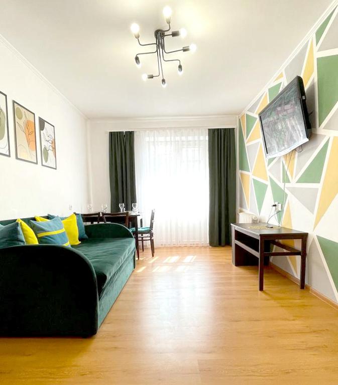 uma sala de estar com um sofá verde e uma mesa em 3 кімнатна затишна та комфортна квартира em Chernivtsi