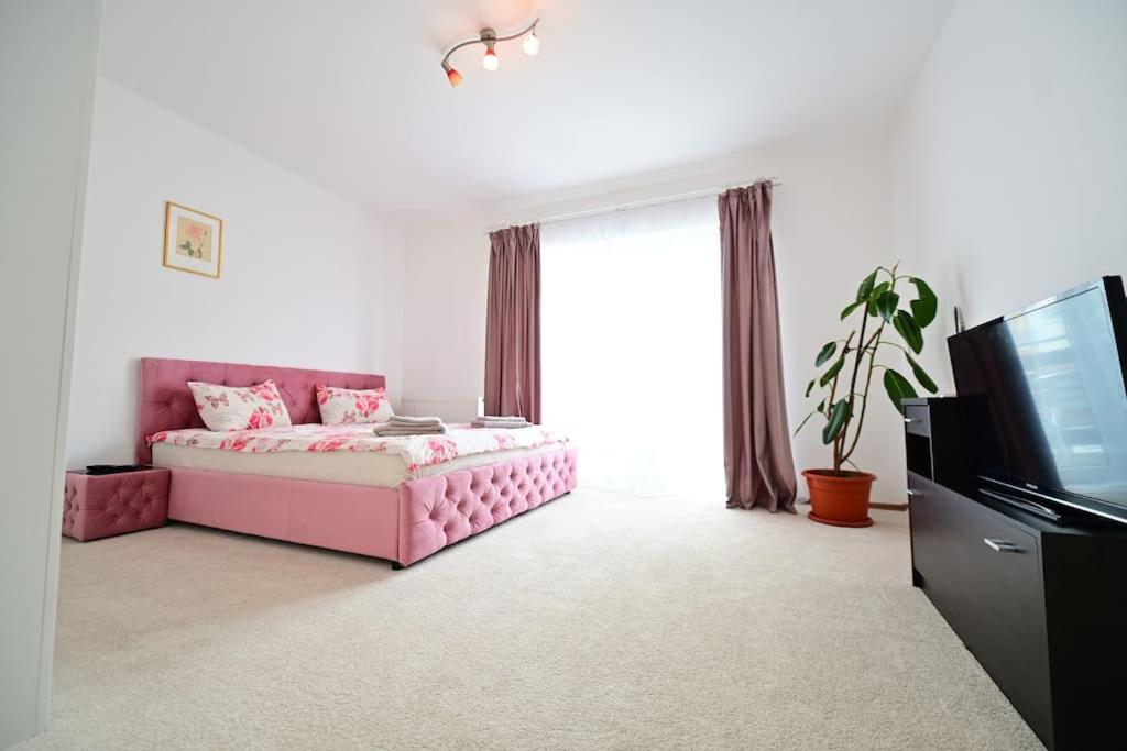 a bedroom with a pink bed and a flat screen tv at Shine in Sibiu in Şelimbăr
