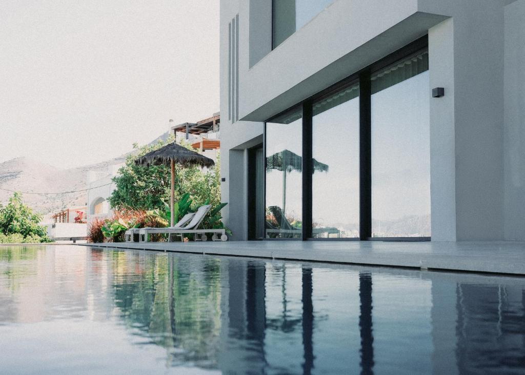 una piscina con un edificio e ombrelloni di Elounda Gulf Sunrise Villa a Eloúnda