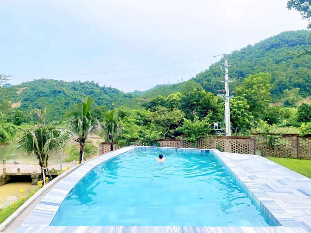 a person in a swimming pool with a mountain in the background at Little Bee in Luong Son