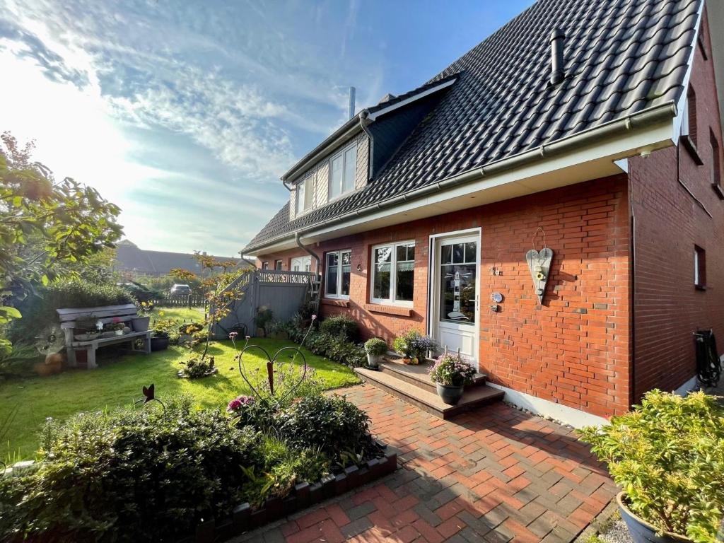 a brick house with a patio and a yard at Ferienwohnung Dünennest in Wittdün