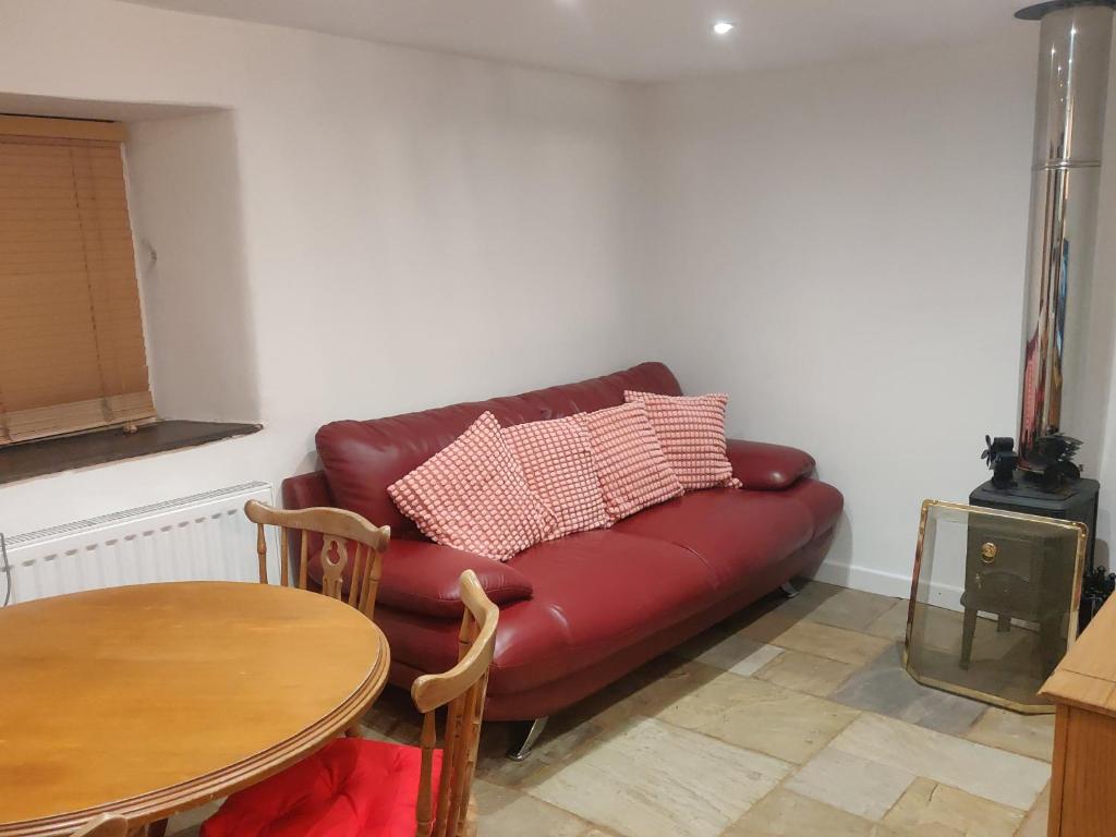 a red leather couch in a living room with a table at The Forge Kington St Michael in Chippenham