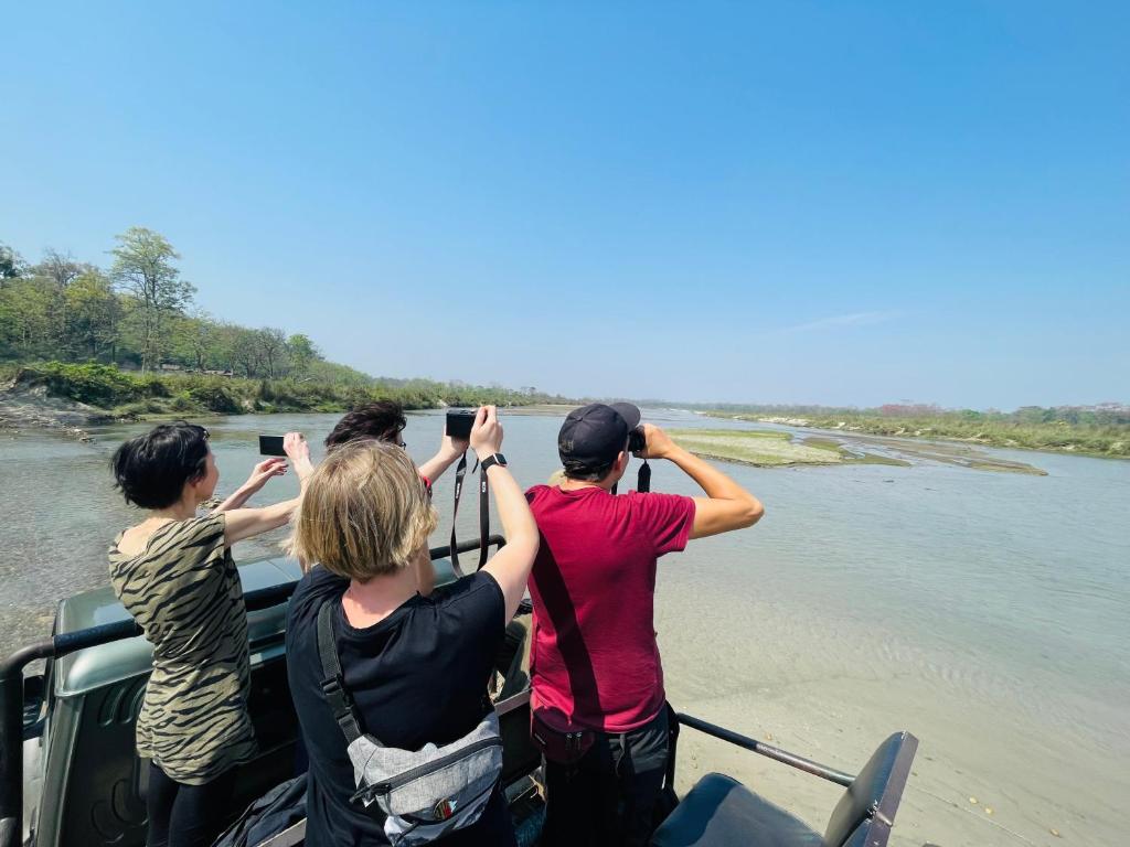a group of people taking pictures on a boat on a river at Hotel Tree Tops- A Serene Friendly Hotel in Sauraha in Chitwan