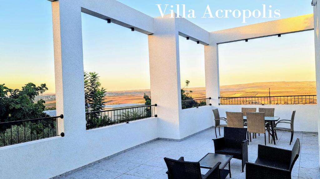 a patio with a table and chairs on a balcony at וילה אקרופוליס Villa Acropolis in ‘En Dor