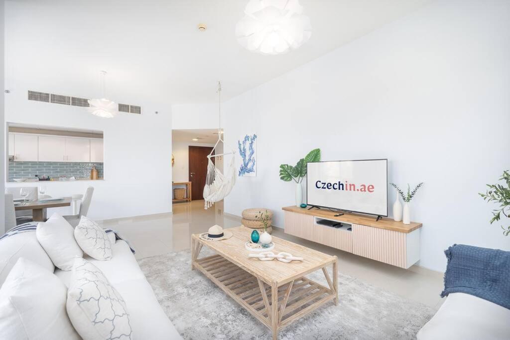 a living room with a white couch and a tv at Contemporary Living by The Sea & 2BD & New Listing in Ras al Khaimah