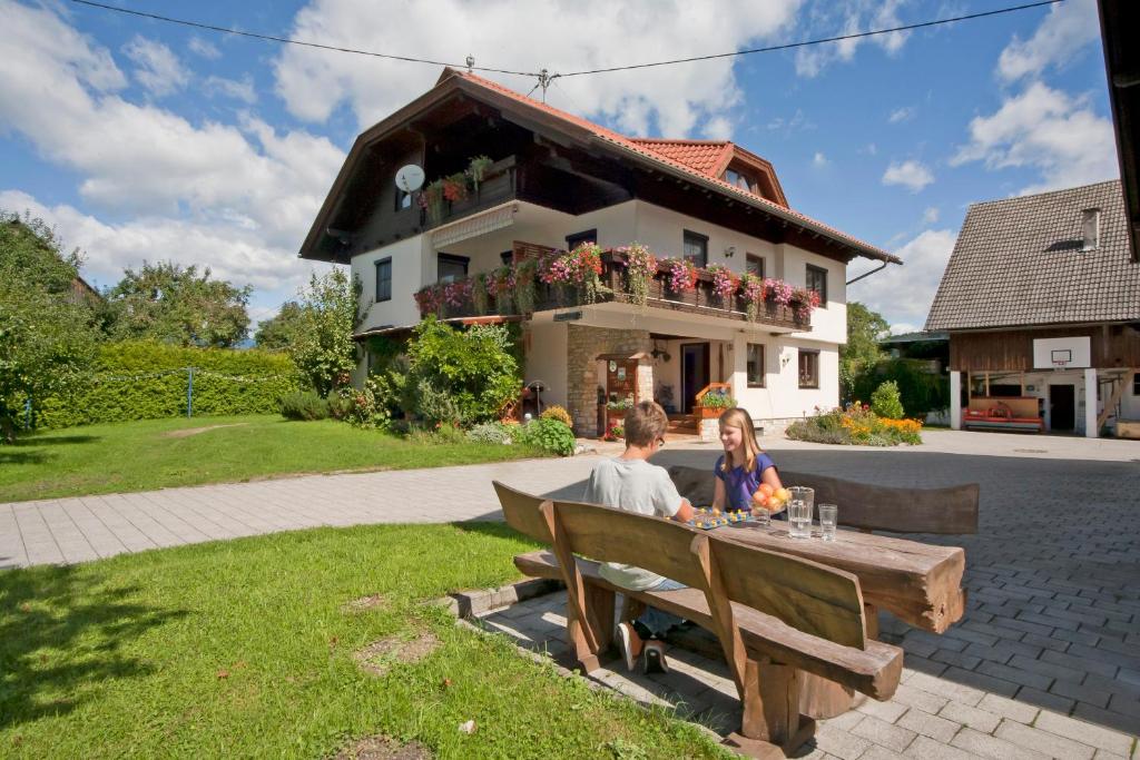 a man and woman sitting at a table in front of a house at Ferienwohnung Sima in Velden am Wörthersee