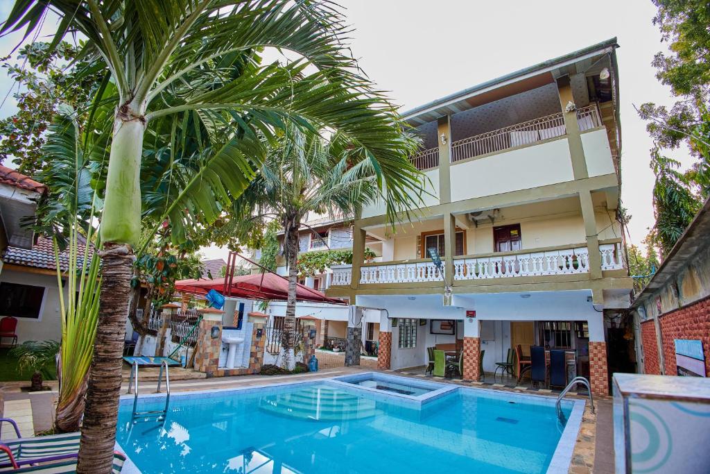 uma piscina em frente a um hotel com uma palmeira em Diani Home Stays em Diani Beach
