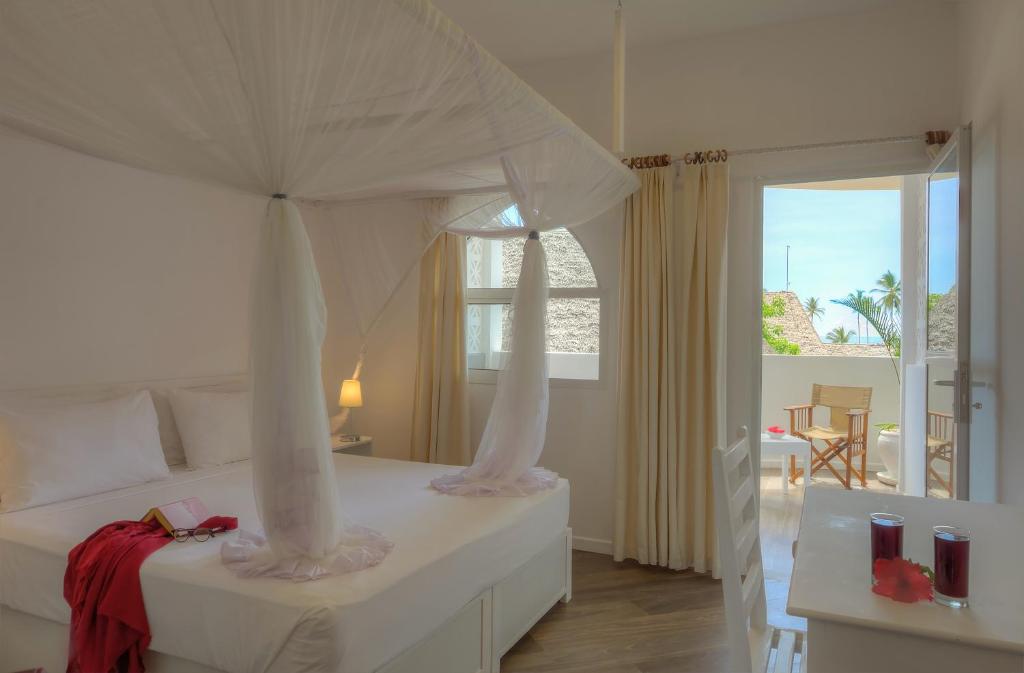 1 dormitorio con 1 cama blanca con dosel en Diamonds Mapenzi Beach - All Inclusive, en Kiwengwa