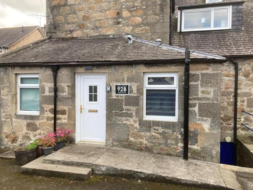 a brick house with a white door and a sign on it at Aberlour Apartment 92 B in Aberlour
